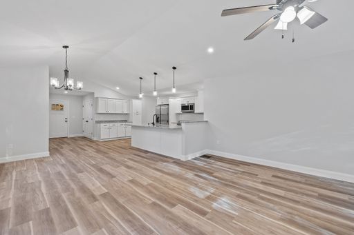 A beautiful newly renovated house corridor with hardwood floors and illuminated hanging lights