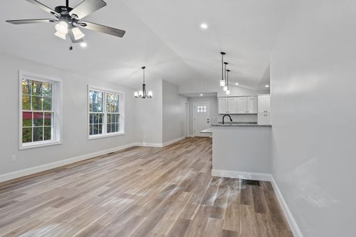 A beautiful newly renovated house corridor with hardwood floors and illuminated hanging lights