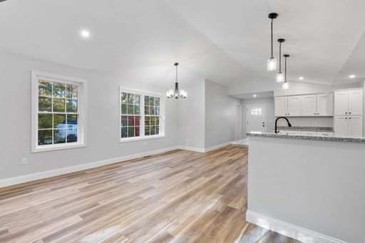 A beautiful newly renovated house corridor with hardwood floors and illuminated hanging lights