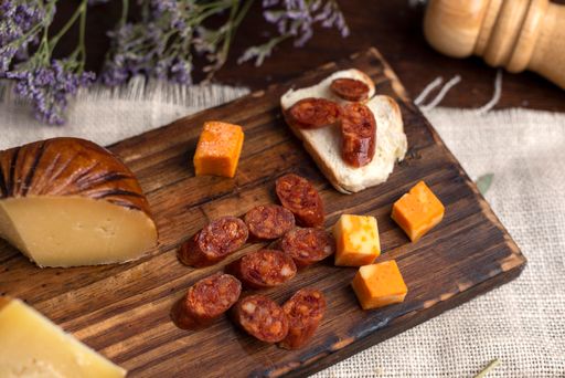 A top view of chorizo spicy pork sausage on a wooden board served with cheese and bread