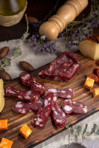 A vertical shot of a wooden board with Soppressata Italian dry salami sausage and cheese