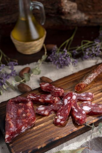 A vertical shot of a wooden board with Soppressata Italian dry salami sausage and chorizo