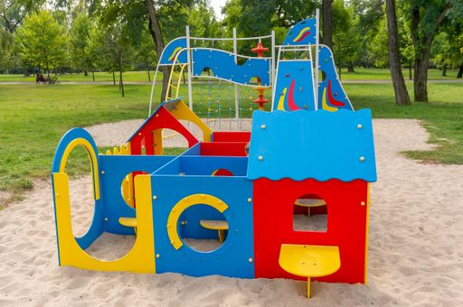 A view of a playground with sand surrounded by trees