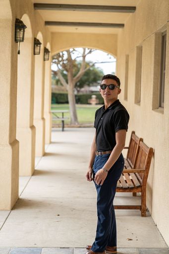 A vertical shot of an attractive young Hispanic man at the building with columns