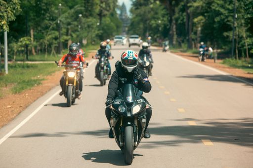 The drivers riding motorcycles on the road in the tropical forest background