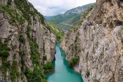 An aerial view of emerald river surrounded by rocky hills in background of mountains
