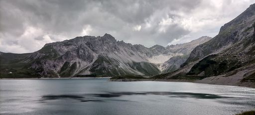 A grayscale shot of a mountains next to the lake