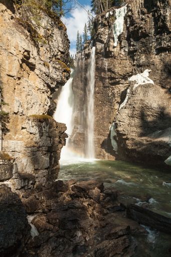 A vertical shot of the waterfall in Johnston Canyon in Canada