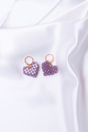 A vertical shot of the purple heart necklace pendants on a white silky cloth