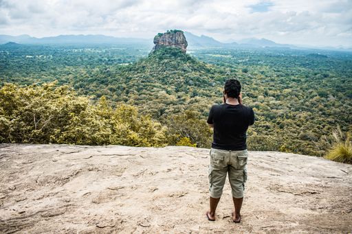 A back view of a man taking pictures of Sigiriya in Sri Lanka