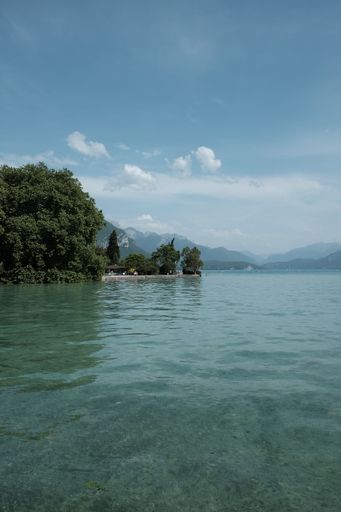 A vertical shot from the shore of Lake Annecy under blue cloudy sky in France