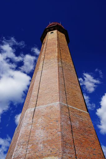 A vertical low angle shot of a lighthouse with a beautiful blue sky and clouds