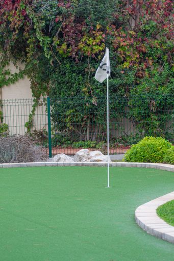 A vertical shot of a number 5 flag over a putt hole on a minigolf course