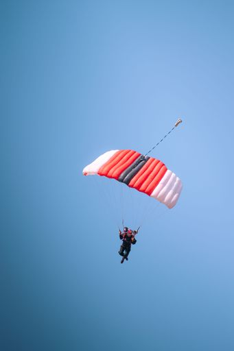 A vertical shot of a parachuter in a clear blue sky during an air show in Pretoria, South Africa