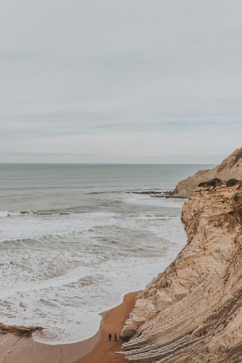 A vertical shot of cliffs surrounded by the sea under a cloudy sky - great for wallpapers