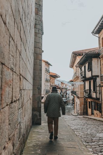 A vertical shot of a male walking on a pavement in brick street in the city on a gloomy day
