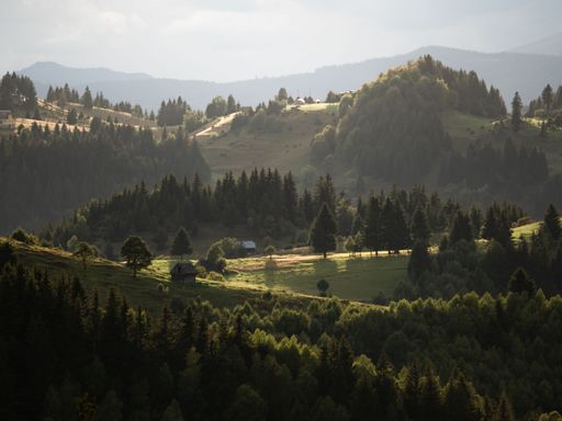 little house on meadow sourrounded by forest in the romanian mountains. Photo
