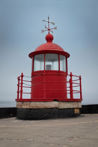 A vertical shot of the unique Nazare Lighthouse against the blue sky background in Portugal