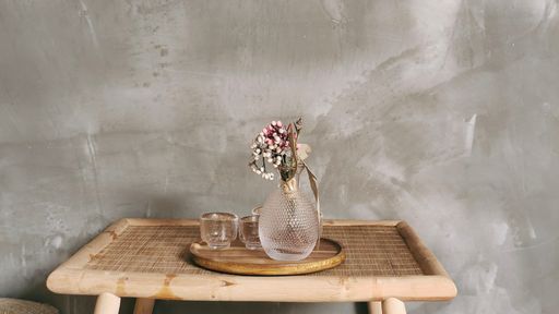 a beautiful shot of flowers in a vase with glasses on a wooden tray on wooden table indoors