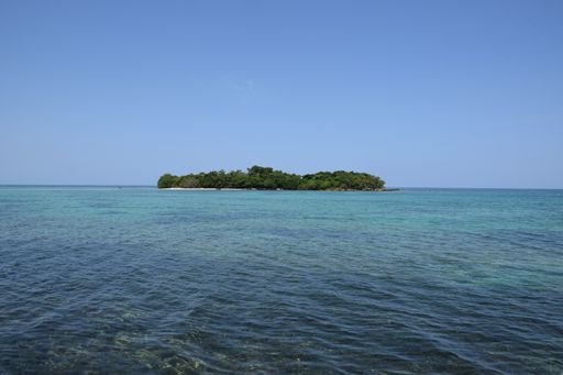 A beautiful green island in the middle of the sea under the clear blue sky
