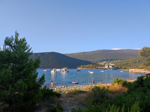 The coast with boats against the background of hills and blue sky. Montenegro.