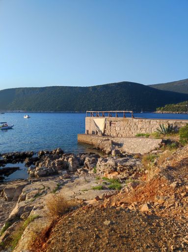 A vertical shot of the empty pier against the background of hills and blue sky. Montenegro.