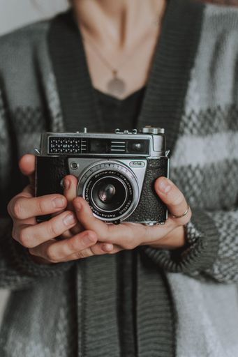 A vertical selective focus shot of a person holding a cool vintage  camera