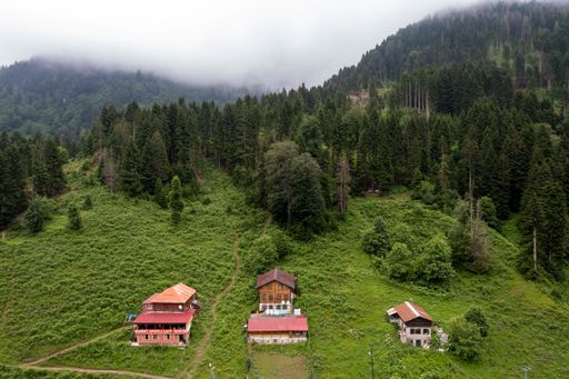 An aerial shot of a travel destination in Trabzon with forested mountains and houses on a gloomy day