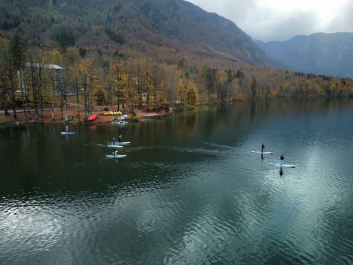 A beautiful shot of a people paddling in a lake surrounded by autumn-colored hills