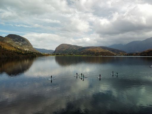 A beautiful shot of a people paddling in a lake surrounded by autumn-colored hills