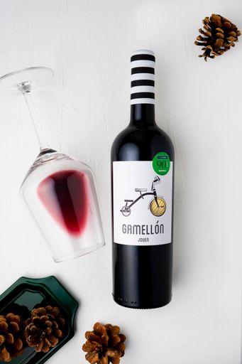 A vertical shot of a bottle of wine and a glass of wine on a white background. Flat lay