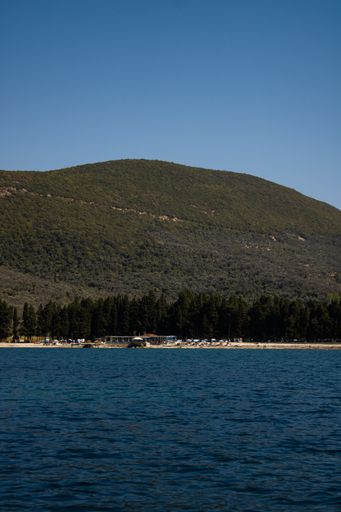 A vertical shot of the sea near a shore with tree covered hills