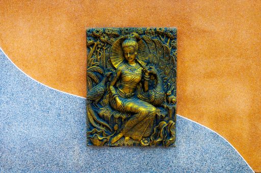 A beautiful carving on a metal plate on a blue and orange wall
