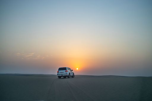 A large off-road jeep driving on the desert at sunset in Doha, Qatar