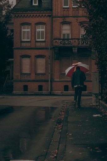 A vertical shot of a man with an umbrella walking down the street. Bad Hersfeld, Germany.