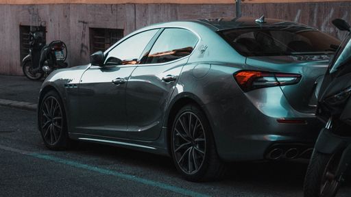 A metallic gray sport car parked along the roadside in an urban setting