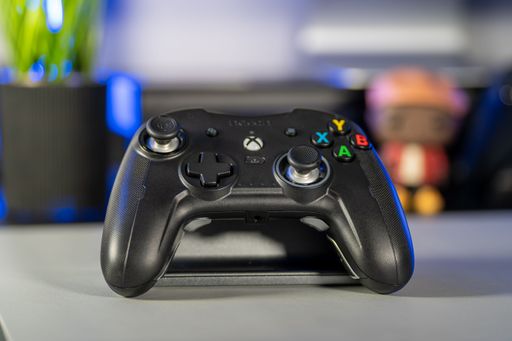 A girl's hand holding a black nacon xbox controller with painted finger nails