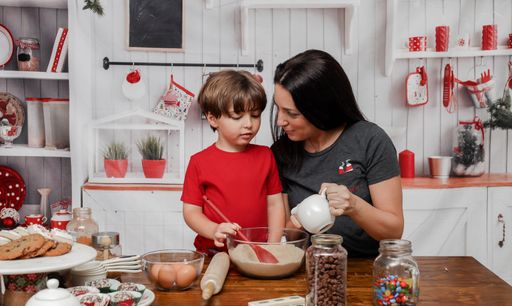 A young little Caucasian boy making dough for cookies with his mom
