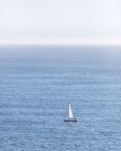 A vertical shot of a sailboat swimming in the large sea