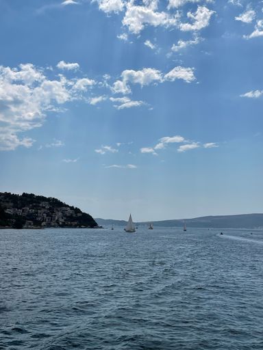 A vertical shot of sailboats in blue sea under blue cloudy sky