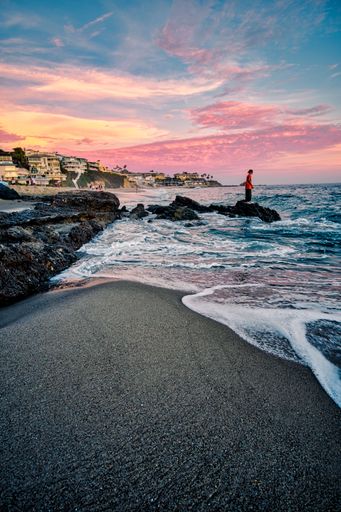 A vertical shot of a person on the beach at sunset