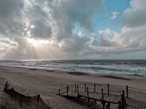 The wooden pier on the sand beach with the sunrise view over the ocean water, Praia de Suave Mar, Esposende, Portugal