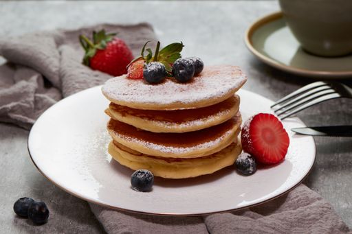 A tasty pancake with sugar powder and fresh strawberries slices