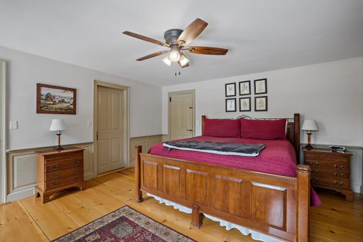 A vintage decoration of a comfortable bedroom with wooden furniture, red bedding and a ceiling fan