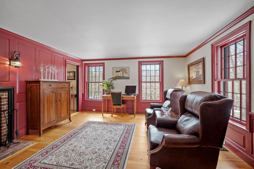 A cozy sitting room furnished in vintage with leather armchairs, wooden furniture and red window heads