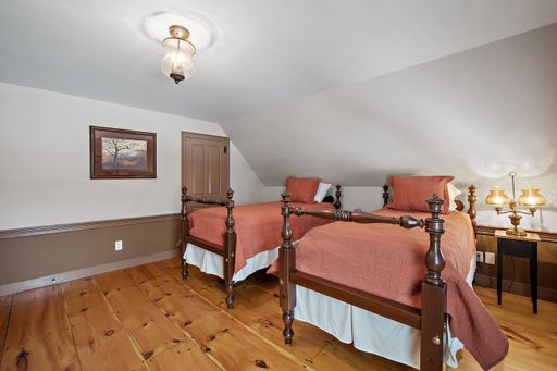 A vintage decoration of a comfortable bedroom with two old style beds and a double hobnail lamp