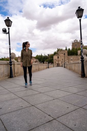 A vertical of a young woman tourist walking through a bridge on a khaki green shirt