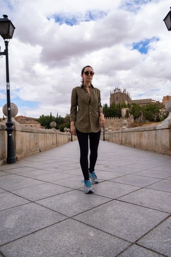A vertical shot of a Young woman on a bridge with beautiful buildings in the background