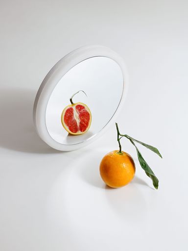 A vertical shot of a red orange in the mirror