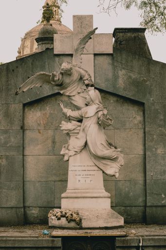 A vertical shot of a religious sculpture in the Chacarita Cemetery in Buenos Aires, Argentina.